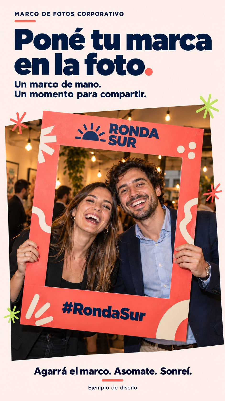 Imagen conceptual de dos personas adultas sosteniendo un marco de fotos corporativo con la marca ficticia Ronda Sur, hueco calado y fondo real del evento visible.