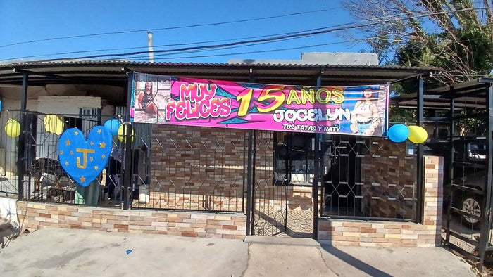 Pasacalle fucsia de cumpleaños de 15 con fotos y globos colgado en el frente de una casa