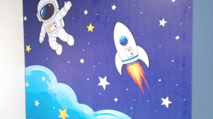 Papel tapiz mural espacial con astronauta, cohete y planeta sobre fondo azul, cubriendo la pared completa