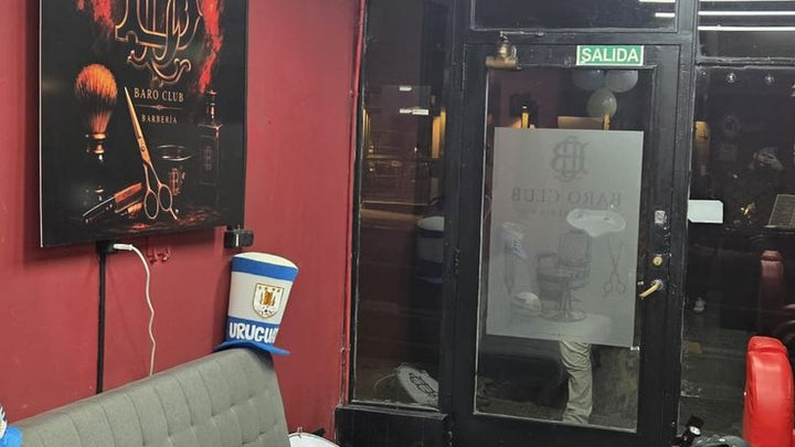 Cartel cuadrado en sintra con diseño de barbería en rojo y negro, colgado en la pared del salón