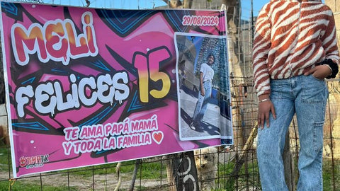 Pasacalle de cumpleaños de 15 en tonos rosados con foto y nombre personalizado, colgado frente a una casa