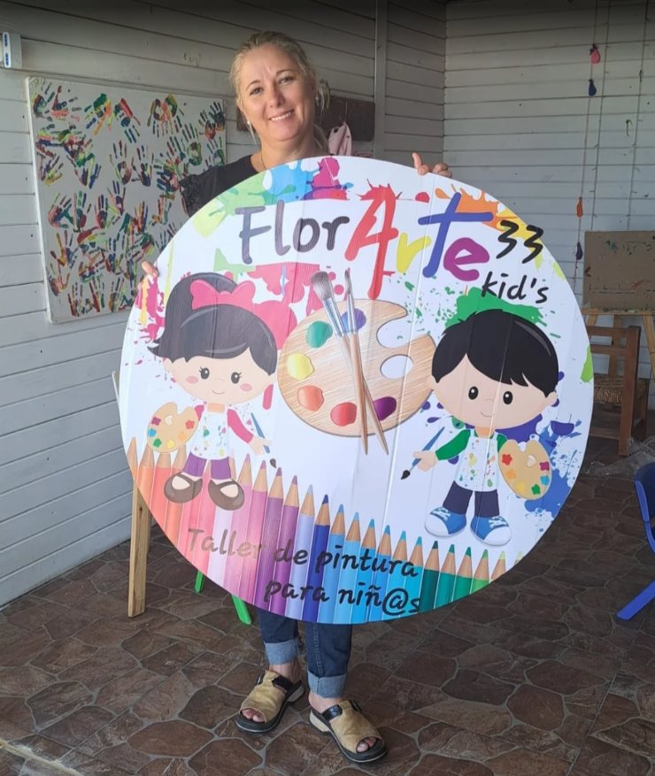 Fondo rígido circular de 1 metro con logo colorido de taller de pintura infantil, sostenido por la clienta