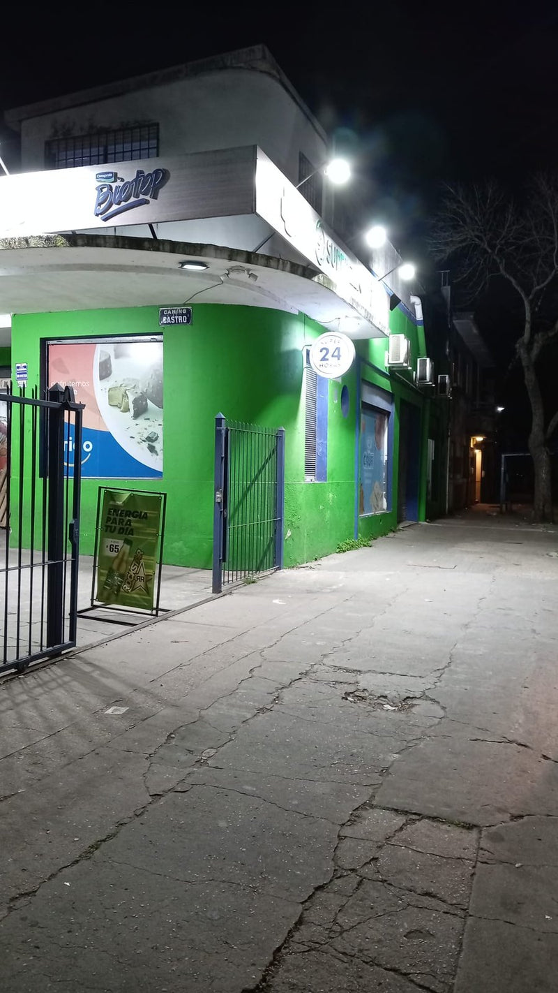 Cartel luminoso LED redondo de 24 horas en la esquina de un supermercado verde iluminado de noche