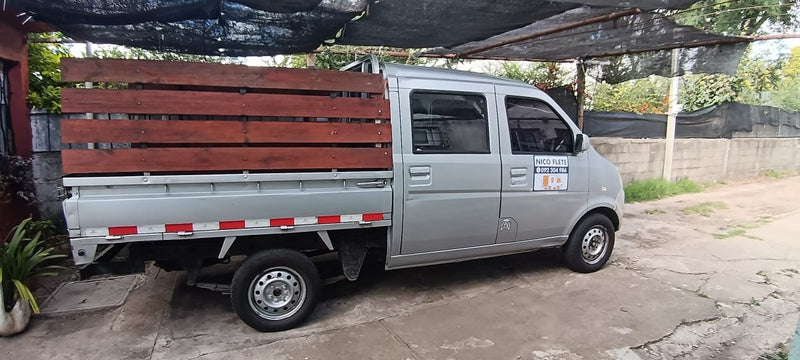 Imán vehicular de fletes en la puerta de una camioneta gris con baranda de madera