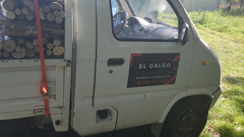 Imán vehicular negro de leñería y fletes en la puerta de un camioncito cargado de leña