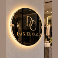 Cartel Lumi Glass de acrilico con logo dorado e iluminacion LED halo en boutique de ropa
