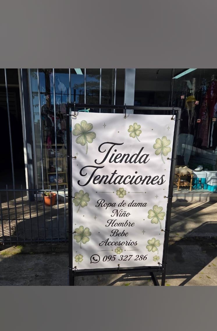 Banner con diseño de tréboles tensado en estructura metálica en la vereda de una tienda de ropa