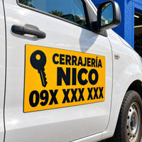Imagen conceptual de un imán vehicular amarillo de una cerrajería ficticia con teléfono enmascarado, aplicado sobre la puerta blanca de un utilitario frente a un taller azul.