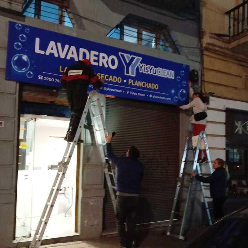Instalación nocturna del cartel Lavadero con trabajadores y escaleras.