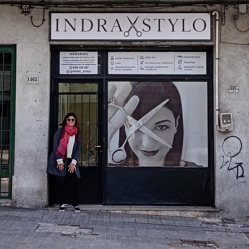 Vidriera ploteada de Indra Stylo con una mujer frente a la peluquería.